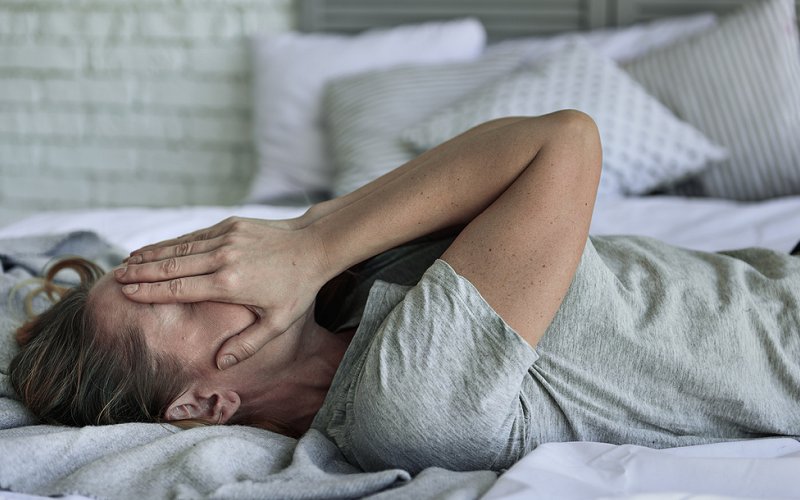 Man in bed with hands upon face