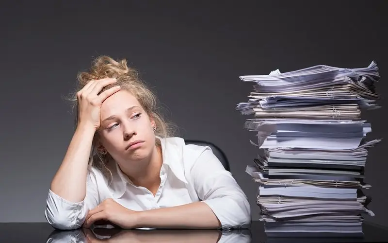 stressed girl looking at pile of books